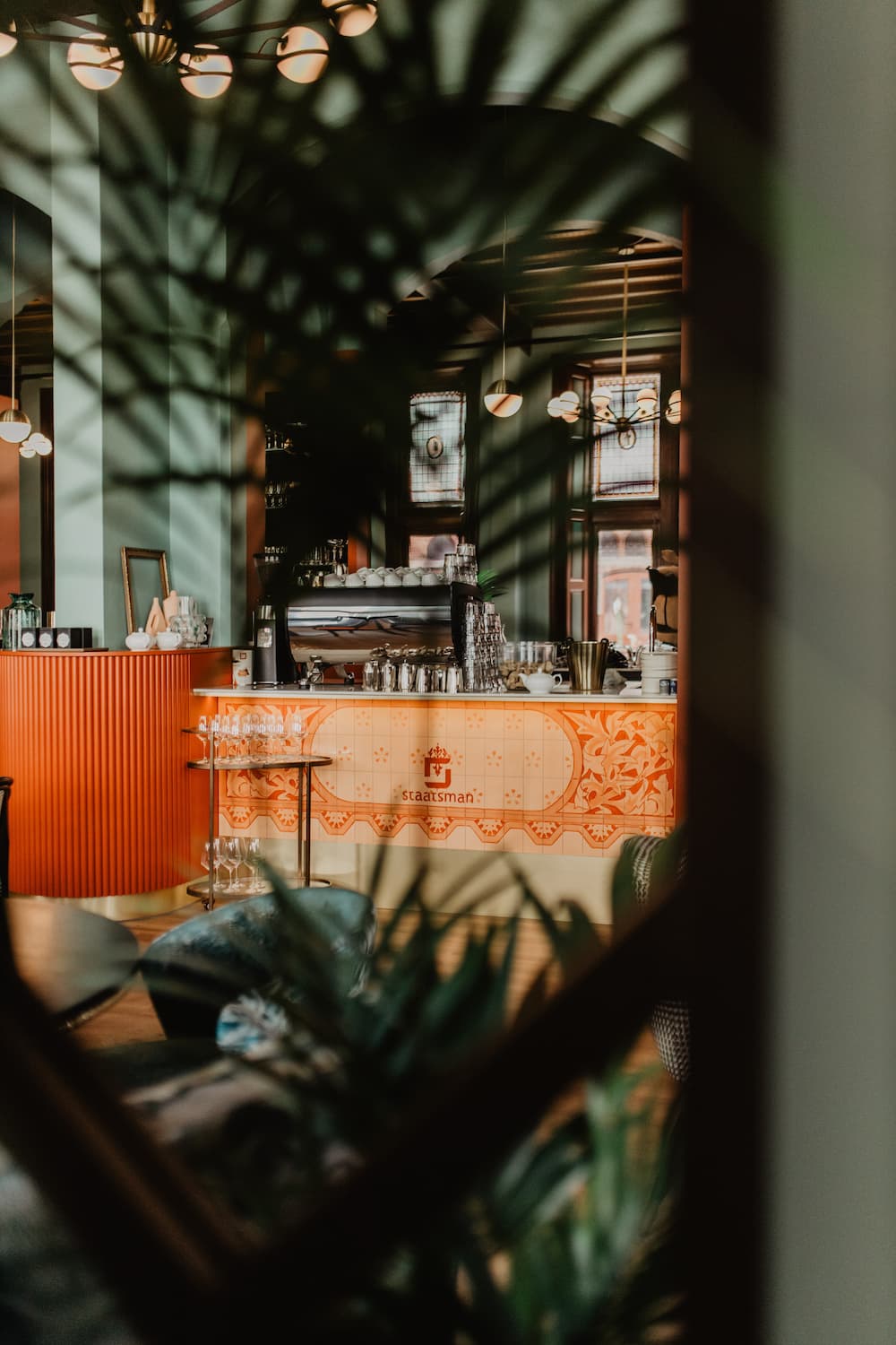 Foto van de bar van Grand Café Staatsman, tussen de planten door genomen