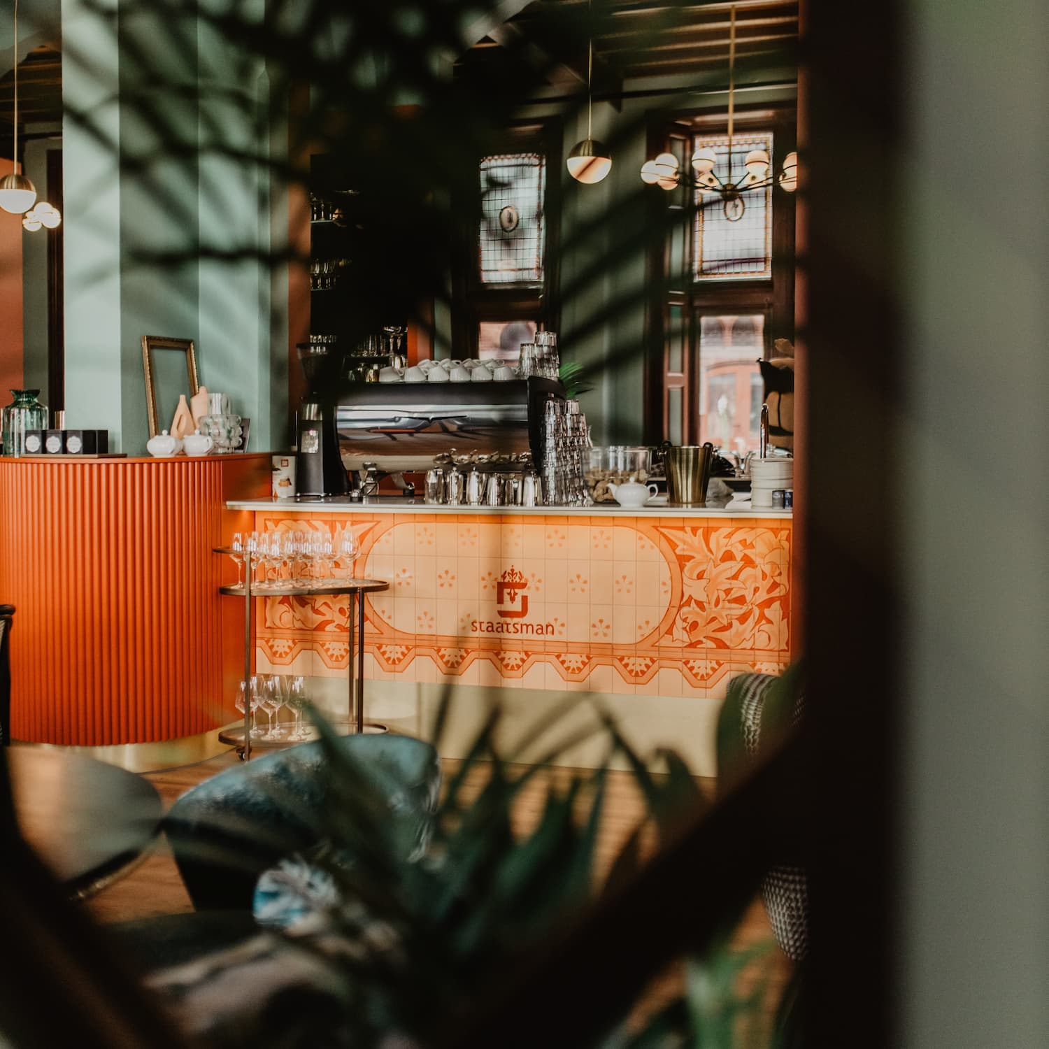 Foto van de bar van Grand Café Staatsman, tussen de planten door genomen